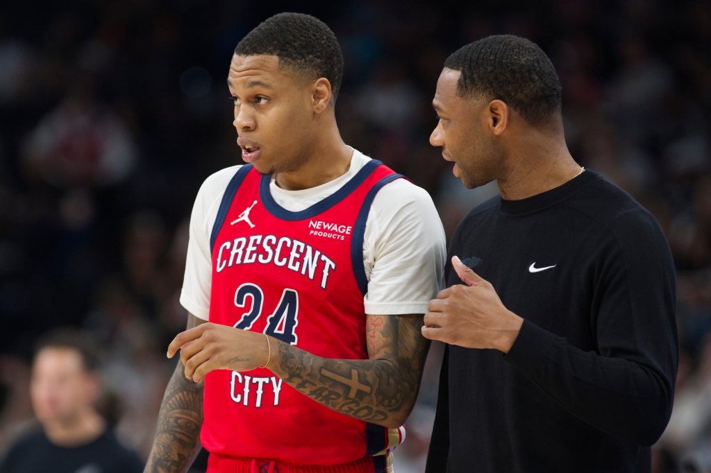 El entrenador en jefe de los New Orleans Pelicans, Willie Green, a la derecha, habla con el senior Jordan Hawkins durante la segunda mitad de un partido de baloncesto de la NBA, el sábado 8 de noviembre de 2025, en San Antonio.