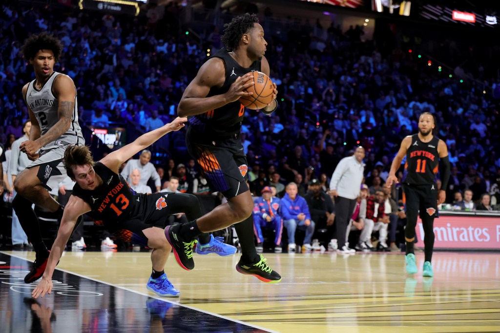 Og Anunoby de los New York Knicks intenta hacer un pase mientras Tyler Kolek de los San Antonio Spurs cae durante un partido de baloncesto.