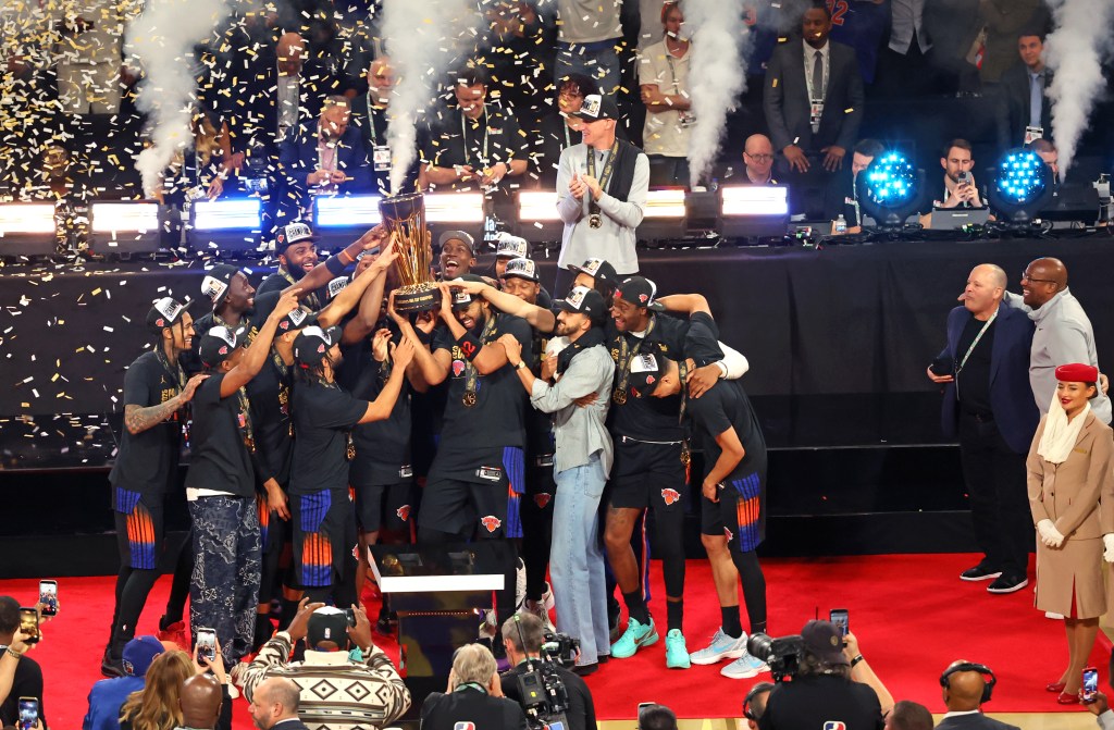 El equipo de baloncesto New York Knicks celebra el trofeo del campeonato de la Copa de la NBA rodeado de confeti y humo.