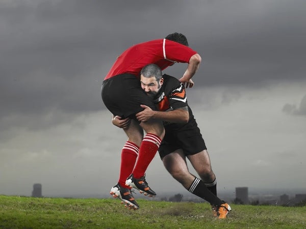 Dos jugadores de rugby poniéndose en forma contra un cielo gris.