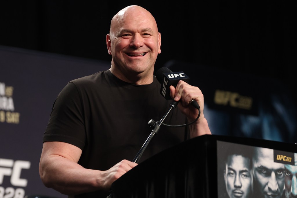 El presidente de UFC, Dana White, sonríe mientras habla por un micrófono en una conferencia de prensa.